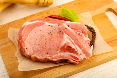 Biber ve tuz ahşap masa arka plan üzerinde yemek pişirmek için hazır çiğ Domuz pirzola