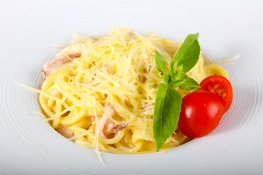 Makarna Carbonara fesleğen yaprakları beyaz tabak içinde hizmet
