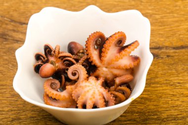 Bebek ahtapot ahşap arka plan üzerinde beyaz tabağına haşlanmış