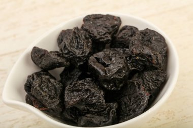 Kurutulmuş Erik yığın kase ahşap arka plan üzerinde 