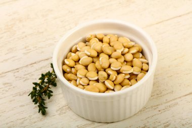 Ahşap arka plan üzerinde kapta çiğ beyaz fasulye