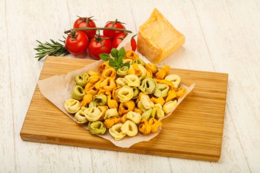 Fesleğenli - ahşap arka plan üzerinde yemek pişirmek için hazır çiğ tortellini