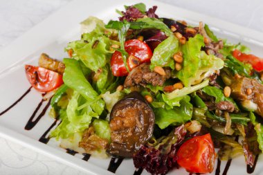 Domuz eti ve beyaz masa üzerinde ızgara sebze salatası