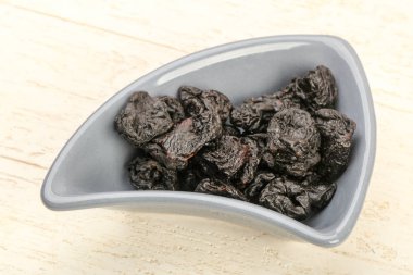 Kurutulmuş Erik yığın kase ahşap arka plan üzerinde 