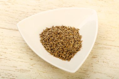 Kimyon tohumları yığın ahşap arka plan üzerinde beyaz kase