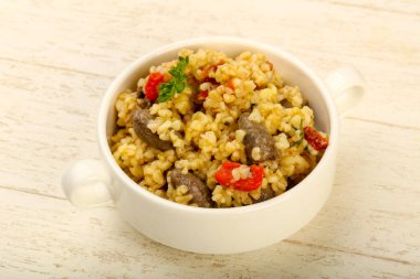 Bulgur tavuk kalpleri ve ahşap arka plan üzerinde kuru domates ile kase