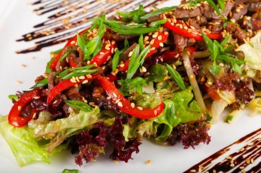 Domuz eti ve beyaz masa üzerinde ızgara sebze salatası