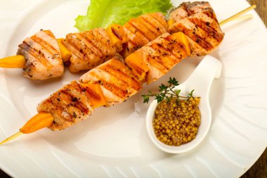 Ahşap mutfak masasında beyaz tabakta Dijon hardal soslu somon ızgara şiş 