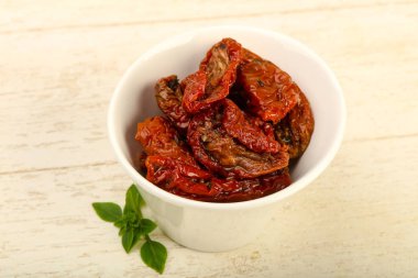 Kase zeytinyağı fesleğen ile kurutulmuş domates yaprakları, ahşap masa arka plan