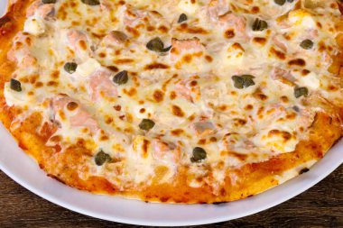 Somon ve Kapari beyaz tabak içinde yumuşak peynirli pizza