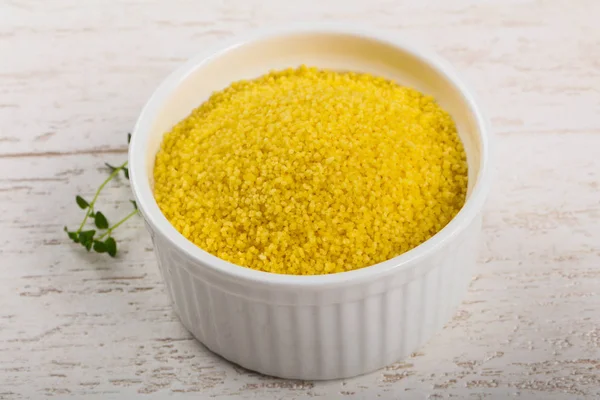 Kekik bir kase içinde ham coiscous ahşap arka plan üzerinde bırakır