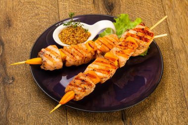 Ahşap mutfak masasında beyaz tabakta Dijon hardal soslu somon ızgara şiş 