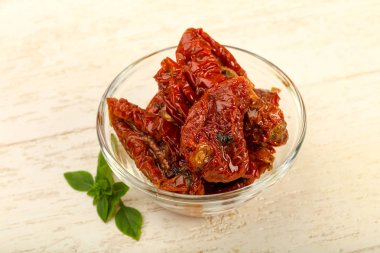 Kase zeytinyağı fesleğen ile kurutulmuş domates yaprakları, ahşap masa arka plan