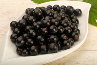 Olgun siyah kuş üzümü yaprağı, ahşap masa arka plan ile kase