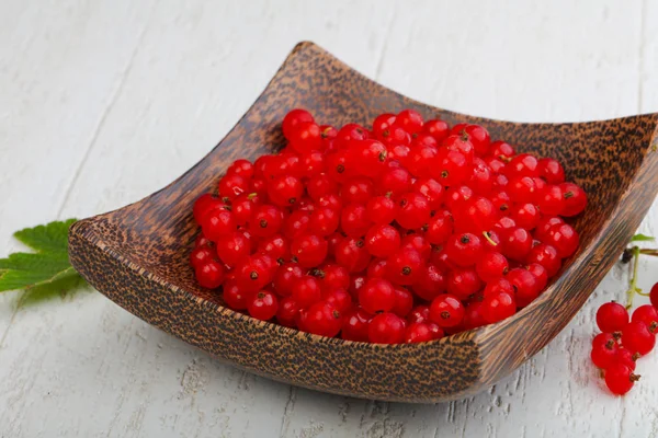 Yapraklarla kase ahşap arka plan üzerinde kırmızı kuş üzümü