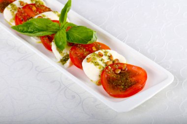 Beyaz tabak içinde taze domates ile İtalyan Caprese salatası