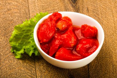 Kase ahşap arka plan içinde suyu ile soyulmuş domates