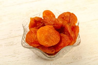 Ahşap arka plan üzerinde kase kuru kayısı yığın