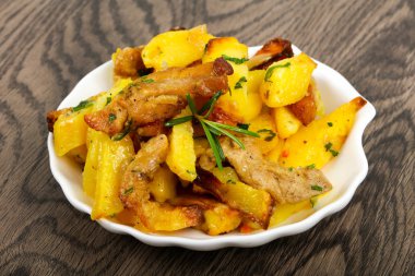 Domuz eti ile kızarmış patates biberiye ahşap arka plan üzerinde hizmet.