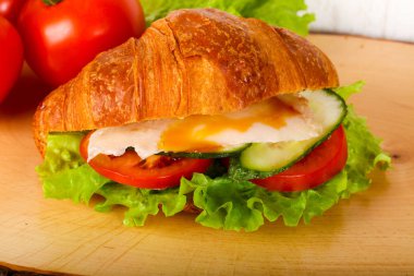 Kruvasan tavuk ve ahşap arka plan üzerinde domates ile