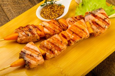 Ahşap mutfak masasında beyaz tabakta Dijon hardal soslu somon ızgara şiş 