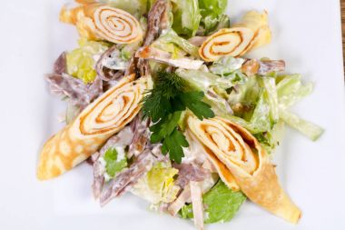 Beyaz tabak içinde sığır eti ve salata yaprakları ile gözleme