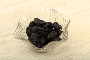 Kurutulmuş Erik yığın kase ahşap arka plan üzerinde 