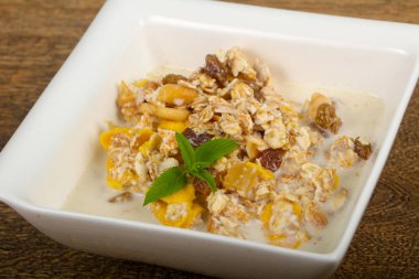 Muz, fındık ve ahşap masa arka plan üzerine nane ile müsli