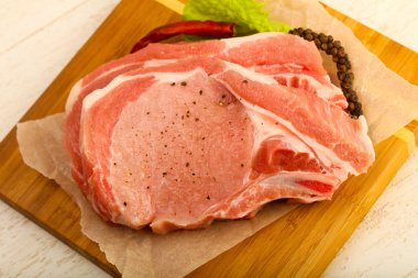 Biber ve tuz ahşap masa arka plan üzerinde yemek pişirmek için hazır çiğ Domuz pirzola