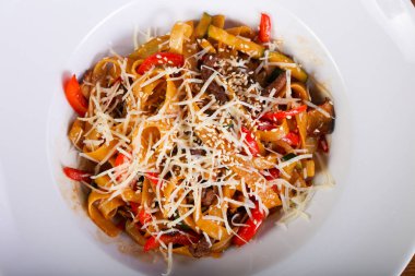 Beyaz tabakta sığır eti ve parmesan peynirli makarna