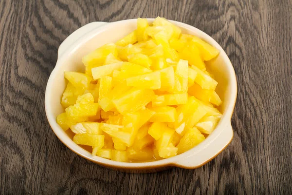 Canned pineapple pieces on wooden table background
