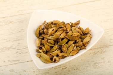 Kuru kakule tohumu yığın kase ahşap arka plan üzerinde 