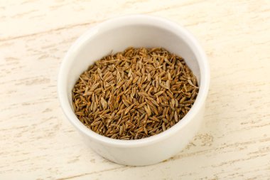 Kimyon tohumları yığın ahşap arka plan üzerinde beyaz kase