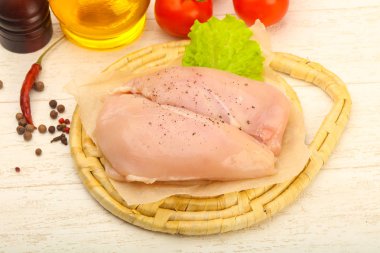 Biber ahşap masa arka plan üzerinde yemek pişirmek için hazır çiğ tavuk göğsü