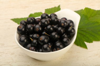 Olgun siyah kuş üzümü yaprağı, ahşap masa arka plan ile kase