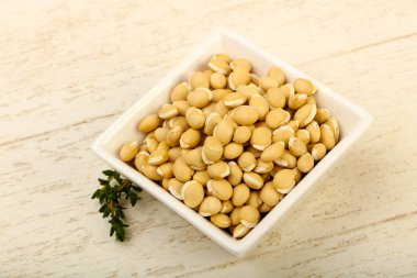 Ahşap arka plan üzerinde kapta çiğ beyaz fasulye