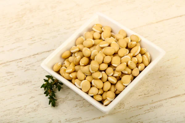 Ahşap arka plan üzerinde kapta çiğ beyaz fasulye