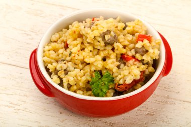 Bulgur tavuk kalpleri ve ahşap arka plan üzerinde kuru domates ile kase