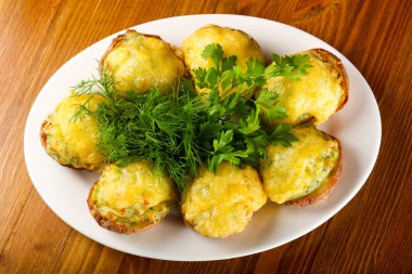 Fırında patates peynir ve ahşap masa arka plan üzerinde otlar ile plaka