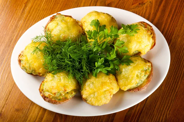 Fırında patates peynir ve ahşap masa arka plan üzerinde otlar ile plaka