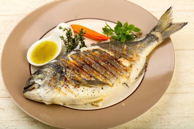 Izgara dorado balık sosu, kekik ve fesleğen ahşap arka plan üzerinde