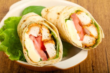 Ahşap arka plan üzerinde tavuk ekmek rulo ile salata yaprakları