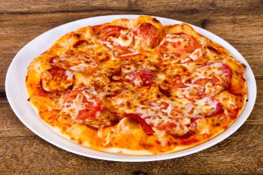 Biberli pizza ahşap arka plan üzerinde peynir ve sosis ile