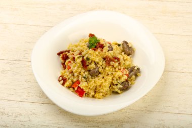 Bulgur tavuk kalpleri ve ahşap arka plan üzerinde kuru domates ile kase