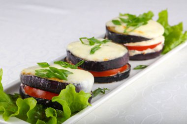 Mutfak masasında beyaz tabakta fırında patlıcan