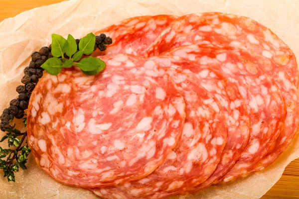 Sliced salami sausage over wooden background