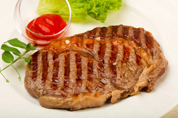 Grilled Rib eye steak with sauce over wooden background