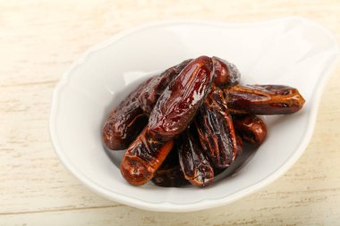 Tatlı meyve yığın kase ahşap arka plan üzerinde tarihleri.