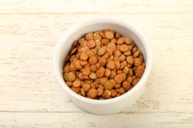 Ahşap arka plan üzerinde yemek pişirmek için hazır bir kapta çiğ mercimek