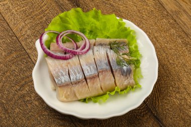 Ahşap arka plan üzerinde ringa balığı filetosu dereotu ve soğan dilimlenmiş